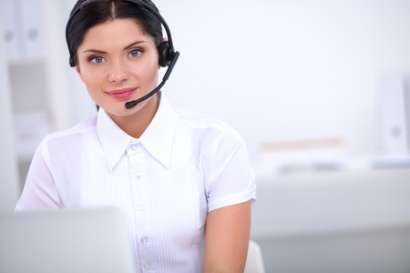 Portrait of beautiful business woman working at her desk with headset and laptopの写真素材