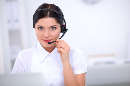 Portrait of beautiful business woman working at her desk with headset and laptopの写真素材