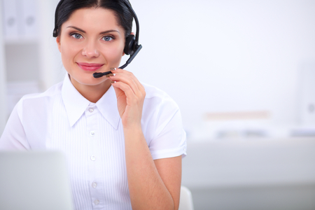 Portrait of beautiful business woman working at her desk with headset and laptopの写真素材