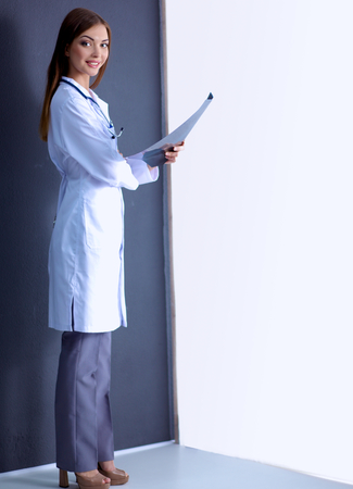 Portrait a female doctor with X-ray picture standing near grey wallの写真素材