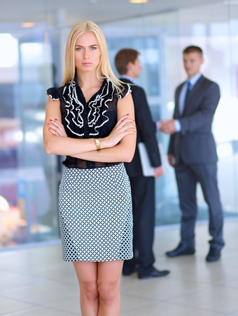 Business woman standing in foreground in office .の写真素材
