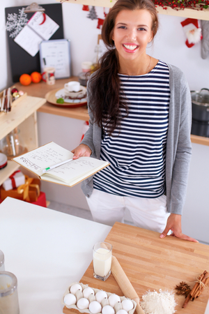 Smiling woman in the kitchen, isolated on christmas backgroundの写真素材