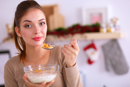 Smiling woman having breakfast in kitchen interiorの写真素材
