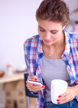 Woman reading mgazine In kitchen at homeの写真素材