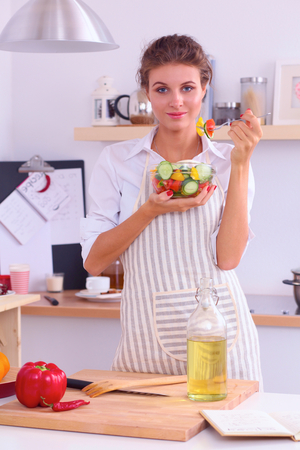 Woman eating fresh salad in modern kitchenの写真素材