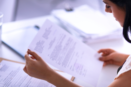 Woman with documents sitting on the desk, in officeの写真素材