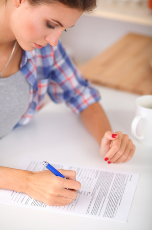 Beautiful young woman writing something in her note pad , isolatedの写真素材
