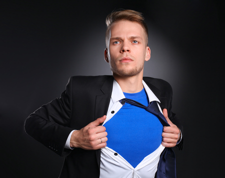 Young businessman acting like a super hero and tearing his shirt, isolated on gray background .の写真素材