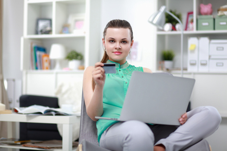 Smiling woman with documents sitting on the desk with laptopの写真素材
