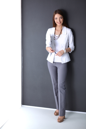 Young woman holding a laptop, standing on gray background.の写真素材
