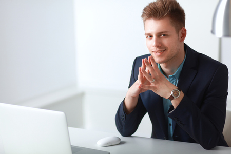 Young businessman working in office, sitting at desk .の写真素材