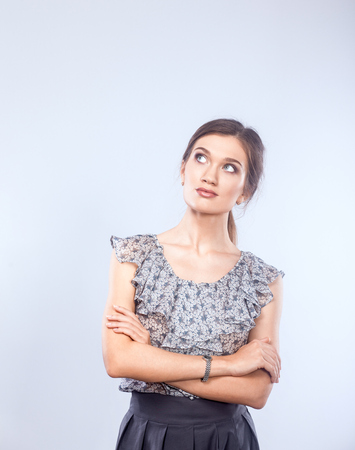 Young woman holding a laptop, standing on gray background.の写真素材