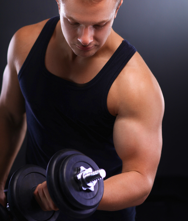 Handsome muscular man working out with dumbbells.の写真素材