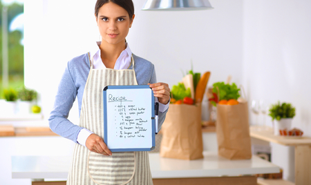 Woman in the kitchen at home, standing near desk with folderの写真素材