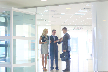 Business woman standing with her staff in background at modern officeの写真素材