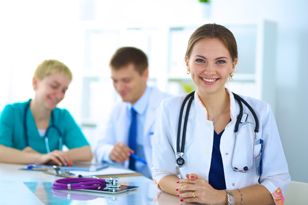 Beautiful young smiling female doctor sitting at the desk.の写真素材