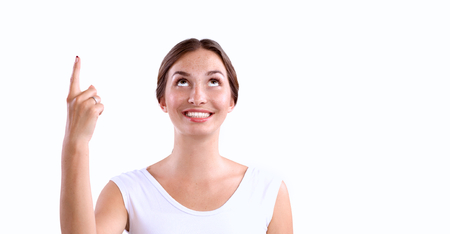Portrait of a smiling young woman pointing up, isolated on white backgroundの写真素材
