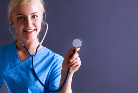 Female doctor with a stethoscope listening, isolated on gray background.の写真素材