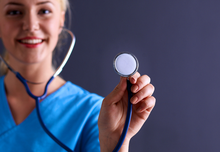 Female doctor with a stethoscope listening, isolated on gray background.の写真素材