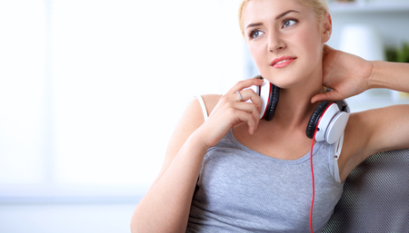 Portrait of young beautiful woman at home sitting on sofa and listening musicの写真素材