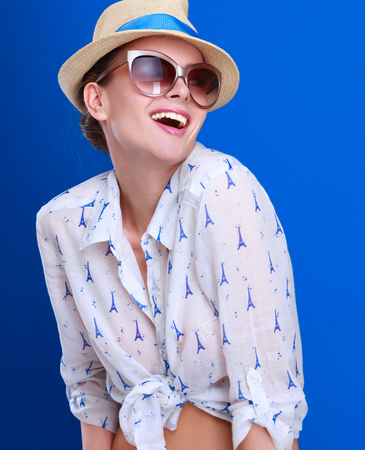 Young woman in hat and sunglasses , isolated on blue background.の写真素材