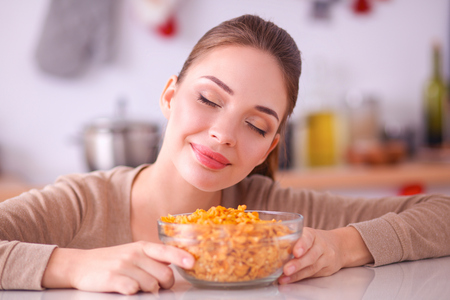 Smiling woman having breakfast in kitchen interiorの写真素材