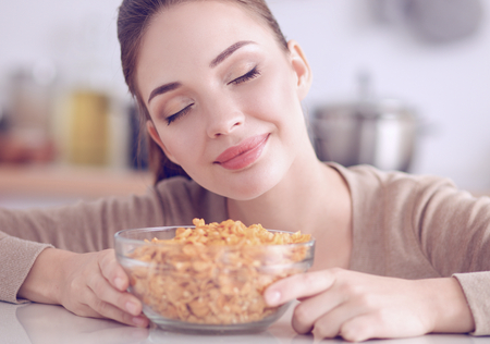 Smiling woman having breakfast in kitchen interiorの写真素材