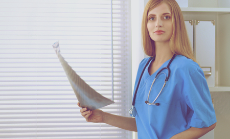 Happy doctor woman is standing in the near windowの写真素材