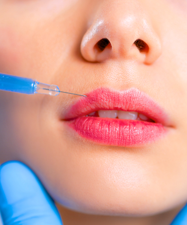 Cosmetic injection on the pretty woman face. Isolated on gray background.の写真素材