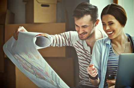 Young couple sitting on the floor and looking at the blueprint of new home.の写真素材