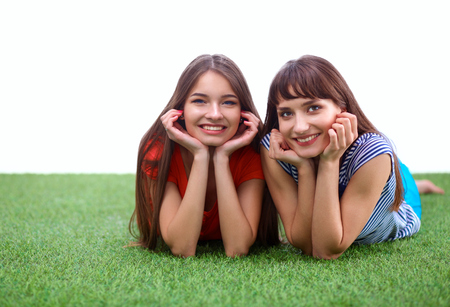 Two young women lying on green grass  .の写真素材