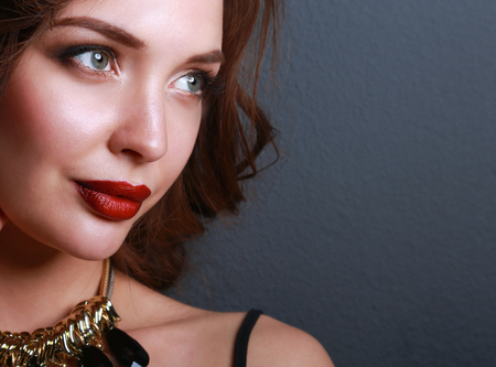 Portrait of young beautiful woman with jewelry, isolated on dark backgroundの写真素材