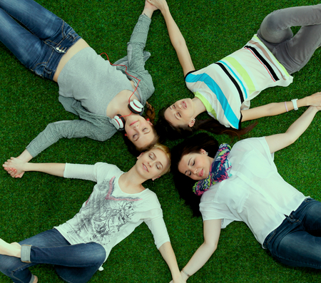 Four young women lying on green grass  .の写真素材