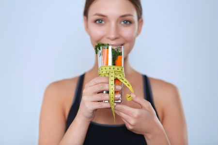 Woman holding a drinking glass full of fresh fruit salad with a tape measure around the glass.の写真素材