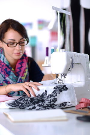 Young woman sewing while sitting at her working place .の写真素材