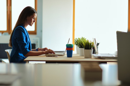 Woman sitting on the desk with laptopの写真素材