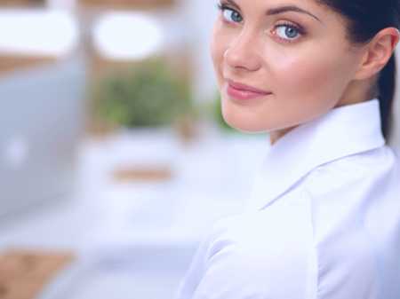 Attractive businesswoman sitting in the office, isolatedの写真素材