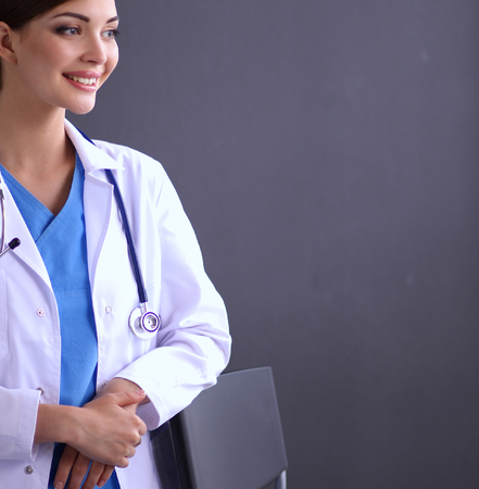Happy beautiful female doctor standing near stool isolated on grey backgroundの写真素材