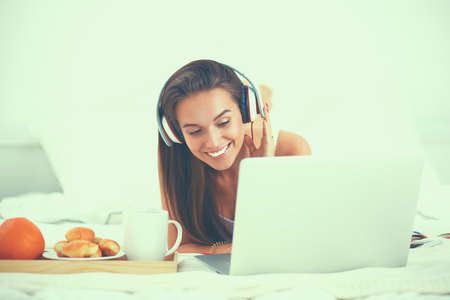 Young beautiful woman in bed listening to music.の写真素材