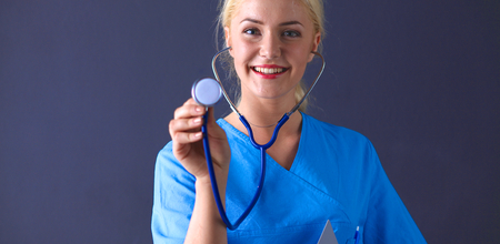Female doctor with a stethoscope listening, isolated on gray background.の写真素材