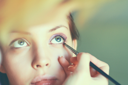 Make up artist doing professional make up of young womanの写真素材