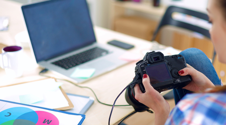 Female photographer sitting on the desk with laptopの写真素材