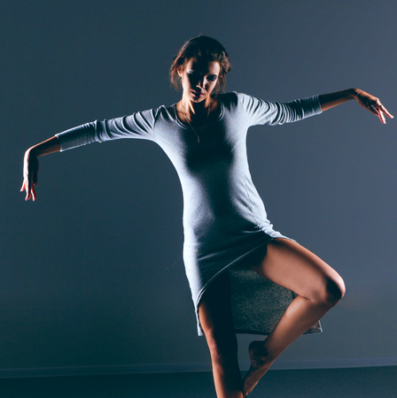 Woman in gray dress barefoot, isolated on dark backgroundの写真素材