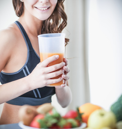 Girl sitting in kitchen on the desk with fruit and glasses juiceの写真素材