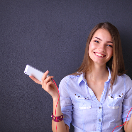Smiling girl with headphones sitting on the floor near wallの写真素材