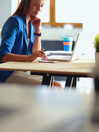 Woman sitting on the desk with laptopの写真素材