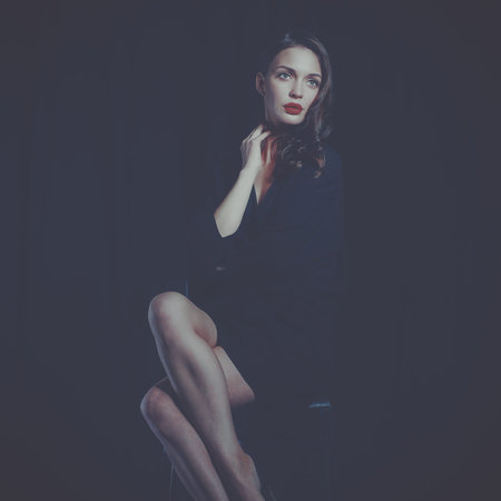 Beautiful woman sitting a chair, isolated on black background