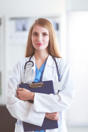 Portrait of woman doctor with folder at hospital corridorの写真素材