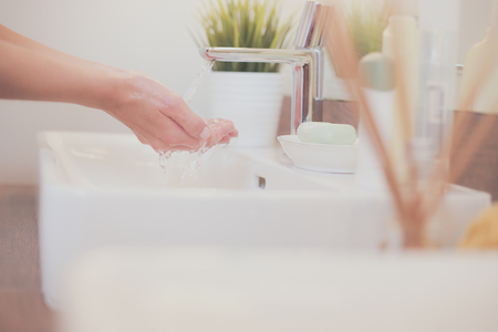 Young woman washing her face with clean water in bathroomの写真素材