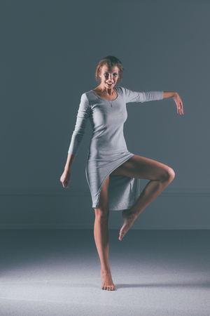 Woman in gray dress barefoot, isolated on dark backgroundの写真素材